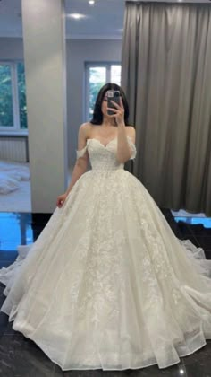 a woman taking a selfie in a wedding dress with her phone up to her face