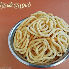 a metal bowl filled with noodles on top of a table