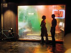 two people standing in front of a neon sign