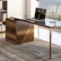 a laptop computer sitting on top of a wooden desk next to a book shelf and window