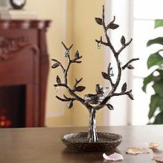 a metal tree with birds on it sitting on a table next to a vase and clock