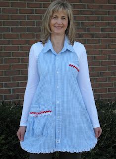 a woman standing in front of a brick wall wearing a blue and white striped shirt