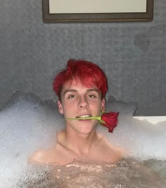 a man with red hair is in the bathtub and has a flower in his mouth