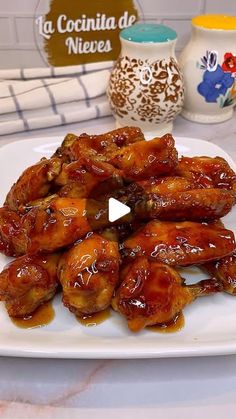 a white plate topped with chicken wings covered in sauce