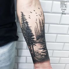 a man's arm with trees and birds in the sky on his left forearm