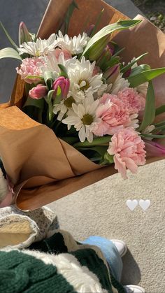 a teddy bear laying on top of a table next to a bouquet of pink and white flowers