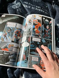 a hand is holding an open comic book