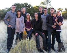 a group of people standing next to each other in front of tall grass and trees