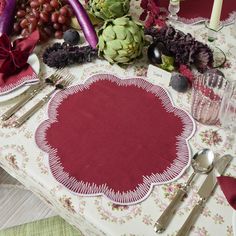 a table topped with plates and silverware covered in red cloth