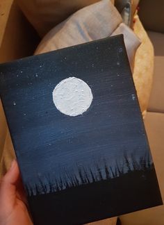 a person holding up a piece of art that looks like the moon in the night sky