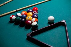 billiards balls and cues on a pool table with triangle shaped rack for cues