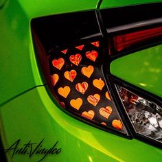 the rear end of a green car with hearts on it