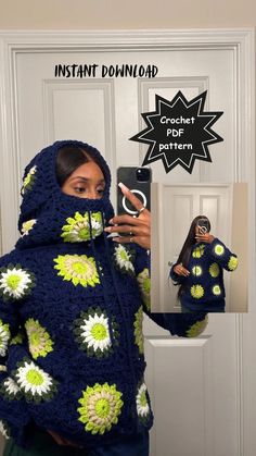 a woman wearing a blue and green crochet hoodie holding a cell phone