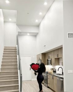 a woman holding a bouquet of red roses in her hand while walking up the stairs