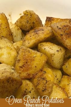 cooked potatoes in a white bowl with seasoning sprinkled on top and the words oven ranch potatoes above it