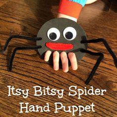 a hand holding a paper spider on top of a wooden table with the words, it'sy bitsy spider hand puppet