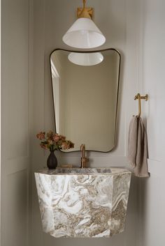 a bathroom sink sitting under a mirror next to a wall mounted faucet with a light on it