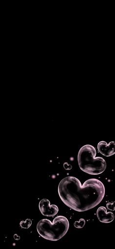 some bubbles in the shape of hearts on a black background