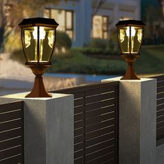 two lamps on top of cement posts near a building