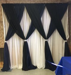 black and white drapes are hanging in front of a wall with blue cloths