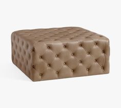 a brown leather ottoman sitting on top of a white floor