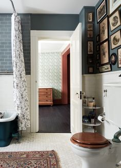 a bathroom with a toilet, sink and bathtub next to a wall with pictures on it