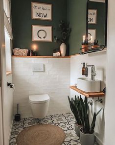 a white toilet sitting next to a sink in a bathroom under two framed pictures on the wall