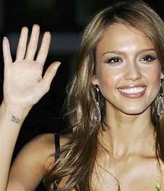 a beautiful young lady waving and holding her hand up