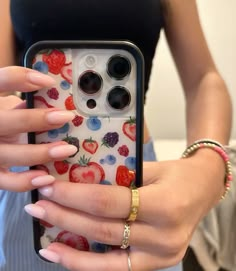 a woman holding up her phone case with strawberries on it