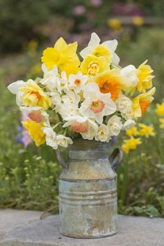 a metal vase filled with yellow and white flowers