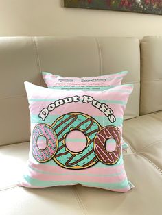 two pillows with donuts on them sitting on a couch