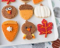 decorated cookies are arranged on a white platter with fall leaves and turkeys in the background