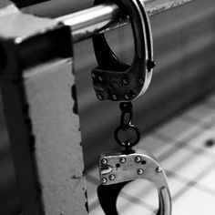 a pair of handcuffs hanging from the handle of a metal rail on a tiled floor