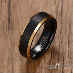 a black and gold wedding ring on top of a wooden table with the words,