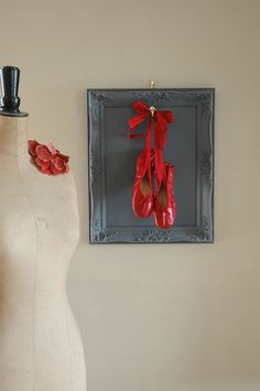 two mannequins with red shoes hanging on the wall