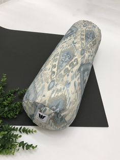 a yoga mat with a pillow on top of it next to a plant and some leaves