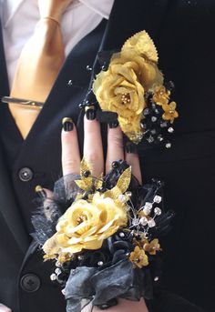 a woman wearing black and yellow flowers on her wrist with gold roses in the middle