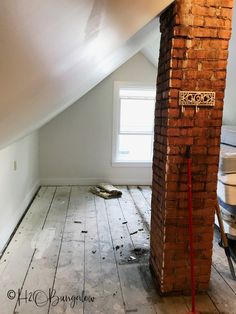 an unfinished room with exposed brick and wood flooring in the attic, including a window