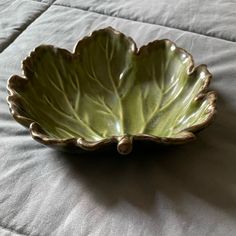 a green leaf shaped bowl sitting on top of a bed