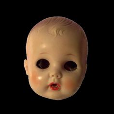 a white doll with black eyes and a red lip on it's head is looking at the camera