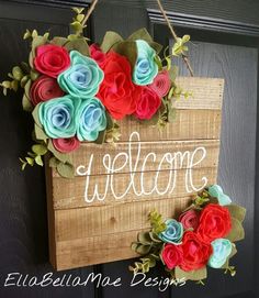 a welcome sign hanging on a door with flowers in the front and behind it that says welcome