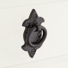 a black door handle on the side of a white wall with an open circle design