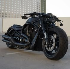 a black motorcycle parked on top of a parking lot next to a tall white building