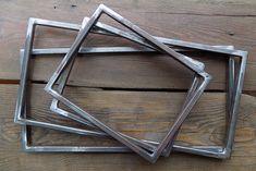 four square metal frames sitting on top of a wooden table