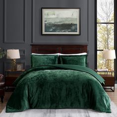 a bed with green comforter and pillows in a room next to a painting on the wall