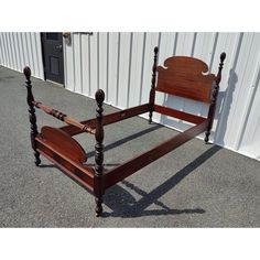 a wooden bed frame sitting in front of a white building