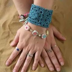 two hands with rings and bracelets on sand