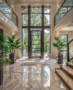 an elegant entry way with large windows and marble flooring, potted plants on either side