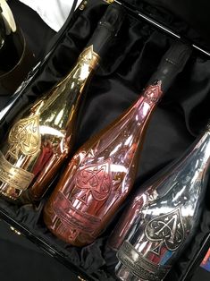 three different types of wine in a black case with gold trimmings on it