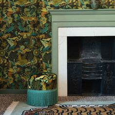 a fireplace in a living room next to a wall papered with flowers and leaves